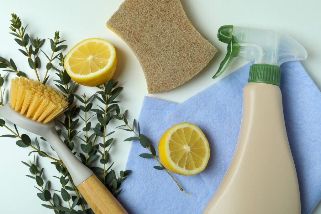 Ekologiska rengöringsredskap med citron, sprayflaska och naturborste på ljus bakgrund
